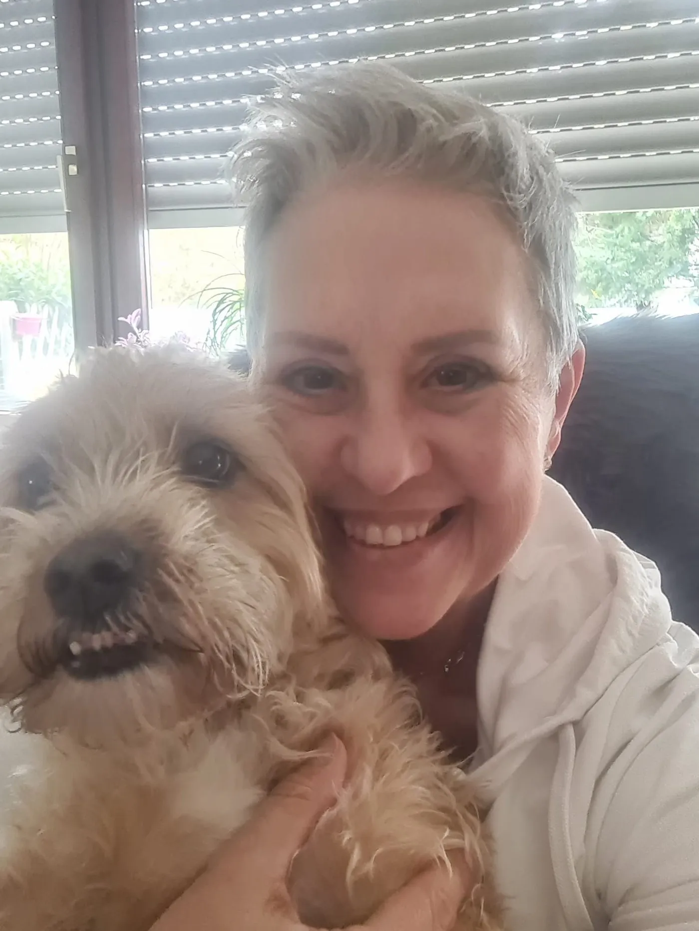 Simone Schmid lächelt in die Kamera, links neben ihr ihr blonder, zotteliger Hund